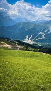 Stunning Alpine Valley View with Lush Green Slopes and Snow Capped Mountains Wallpaper