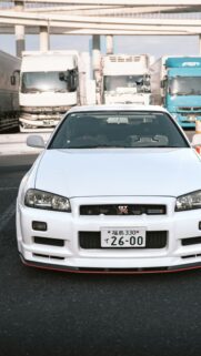White Nissan Skyline GT-R R34 Standing in Truck Parking Mobile Wallpaper
