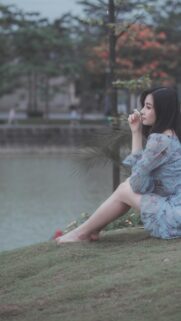 Dreamy Asian Girl in Floral Dress Sitting by the Lake Mobile Wallpaper
