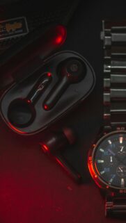Sleek Black Earbuds and Metal Watch with Red Neon Lighting Mobile Wallpaper