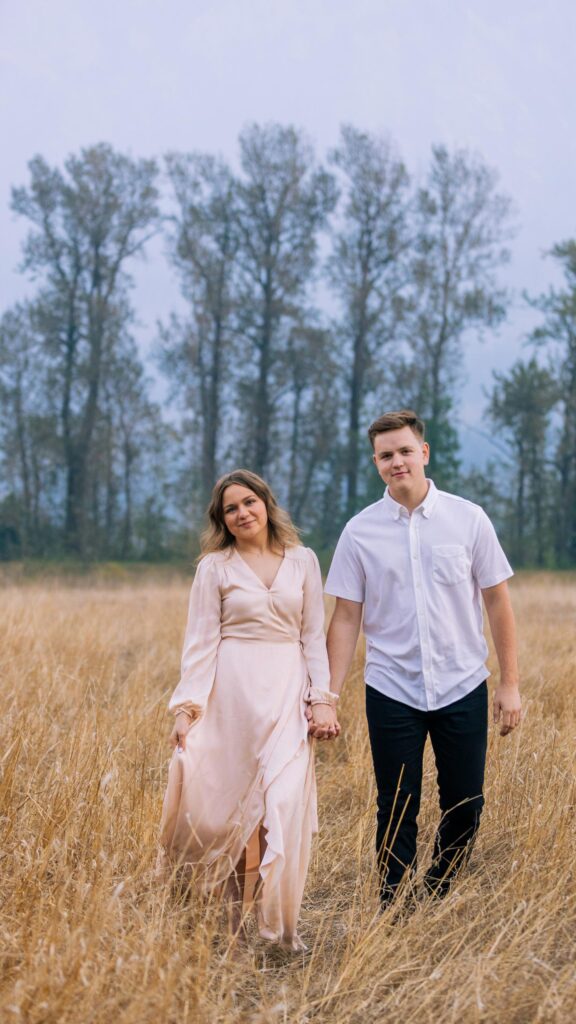 Young Couple Walking Hand in Hand Through Golden Field Wallpaper
