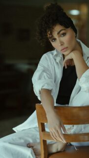 Elegant Woman With Curly Hair and White Shirt Portrait Phone Wallpaper