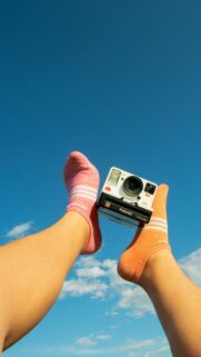 Playful Feet with Polaroid Camera Against Clear Blue Sky Wallpaper