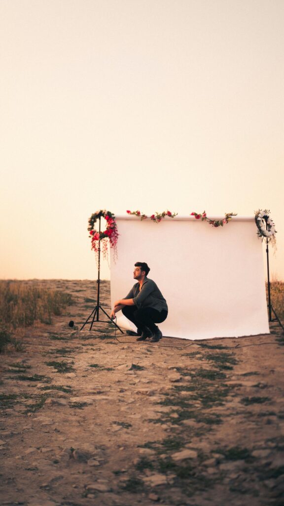 Lonely Man Crouching by Floral Backdrop at Sunset Mobile Wallpaper