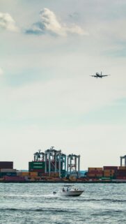 Jet Plane Flying Over Shipping Port and Speedboat Mobile Wallpaper