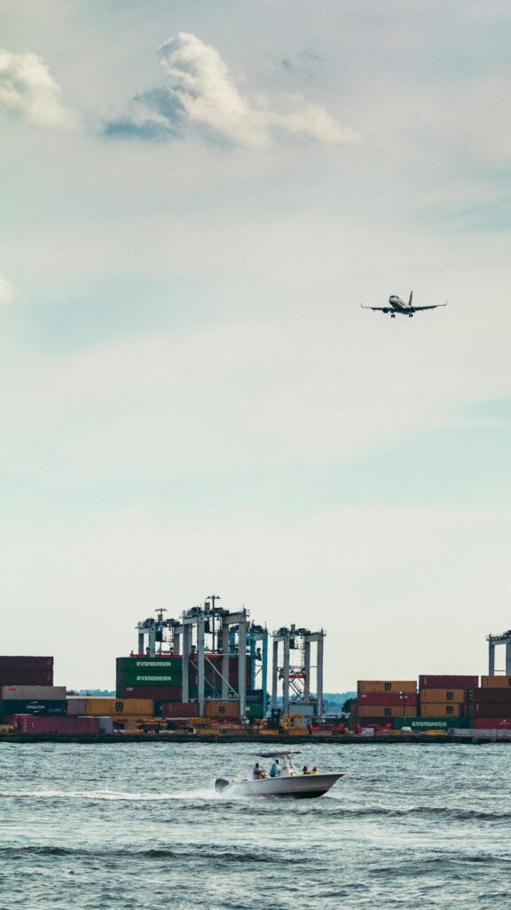Jet Plane Flying Over Shipping Port and Speedboat Mobile Wallpaper