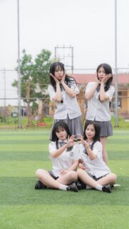 Cute Schoolgirls Making Heart Hands on Grass Field Mobile Wallpaper