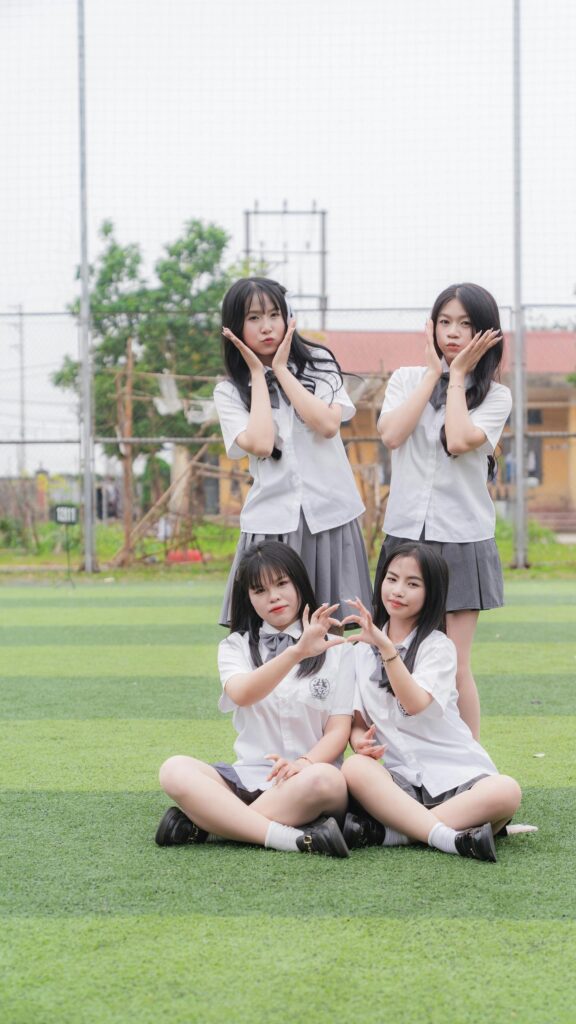 Cute Schoolgirls Making Heart Hands on Grass Field Mobile Wallpaper