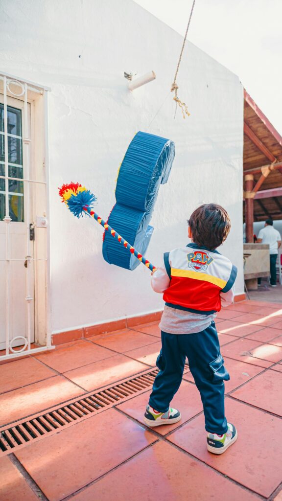 Joyful Child Hitting Piñata at Birthday Celebration Mobile Wallpaper