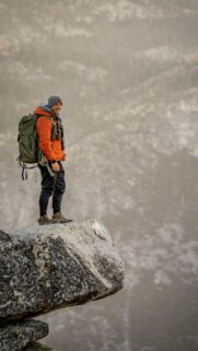 Smiling Hiker Standing on Mountain Edge Peak Mobile Wallpaper