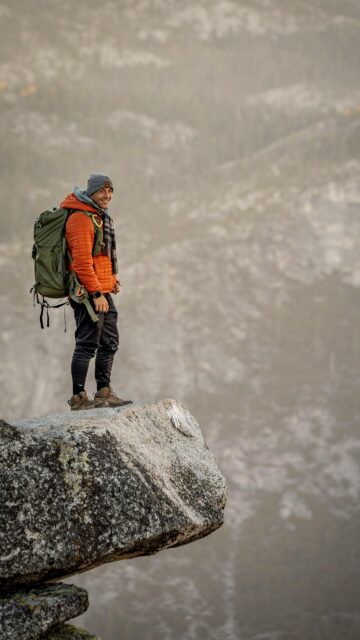 Smiling Hiker Standing on Mountain Edge Peak Mobile Wallpaper