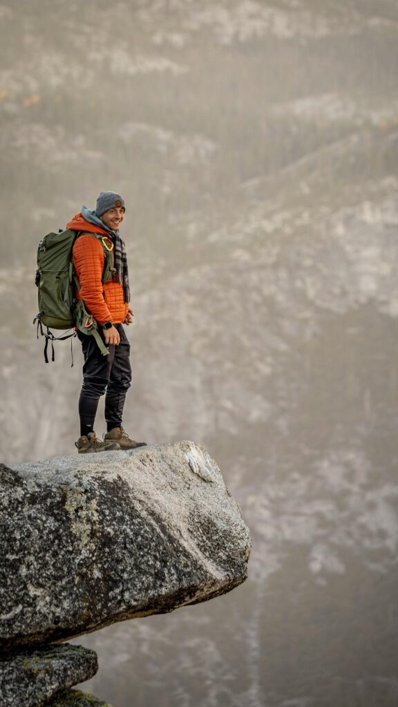 Smiling Hiker Standing on Mountain Edge Peak Mobile Wallpaper