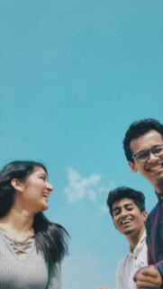Group of Happy Friends Laughing Together Against Clear Blue Sky Wallpaper