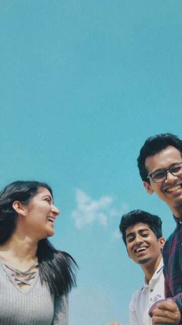 Group of Happy Friends Laughing Together Against Clear Blue Sky Wallpaper