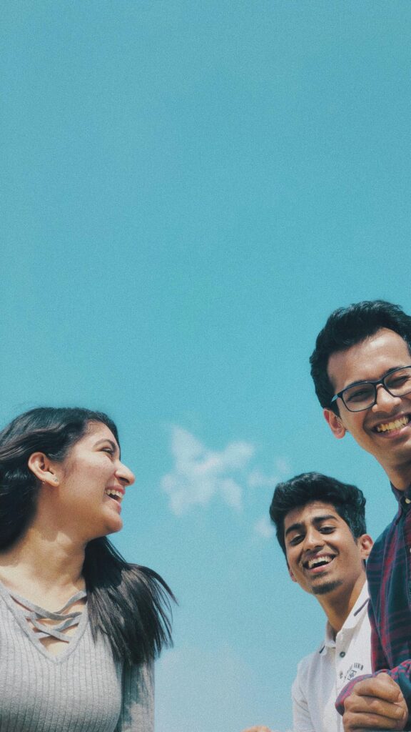 Group of Happy Friends Laughing Together Against Clear Blue Sky Wallpaper