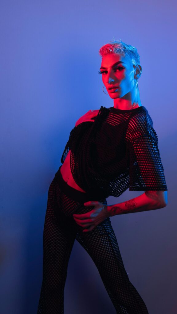 Edgy Queer Fashion Model with Neon Blue and Red Lighting Wallpaper