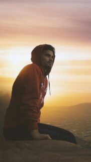 Young Man in Red Hoodie Watching Sunset Over Valley Wallpaper