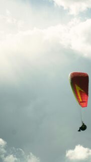 Paraglider Soaring Through Dramatic Cloudy Sky Mobile Wallpaper