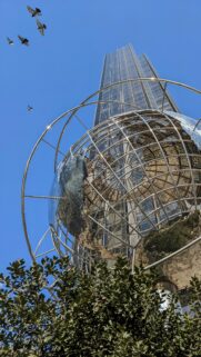 Stunning Steel Globe Sculpture Under a Skyscraper Mobile Wallpaper