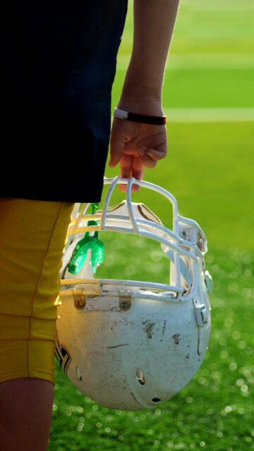 American Football Player Holding Helmet and Mouthguard Mobile Wallpaper