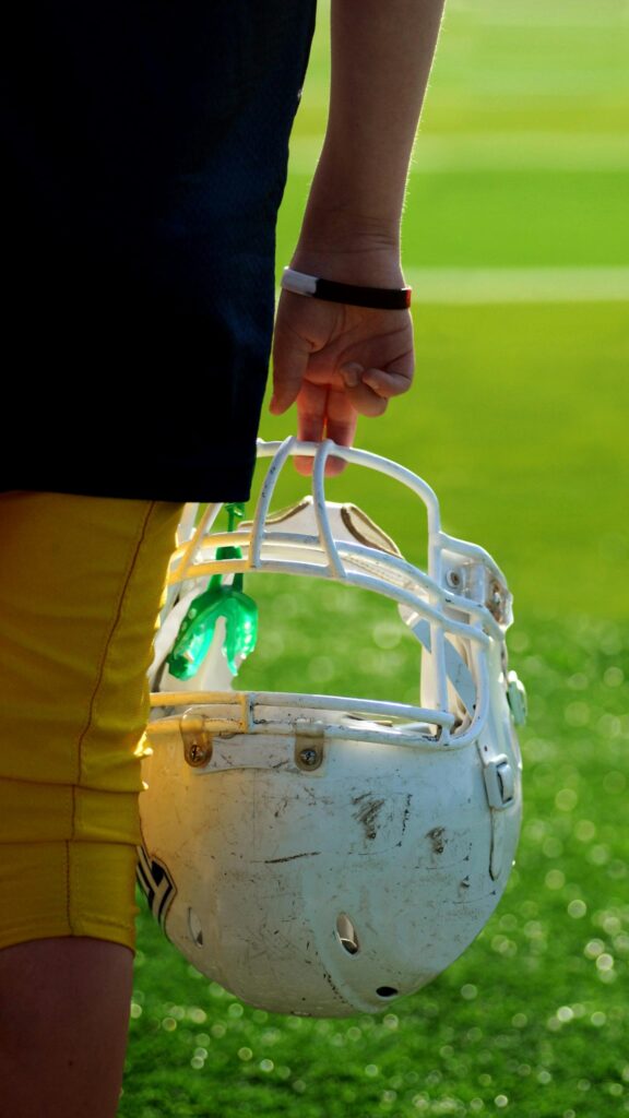 American Football Player Holding Helmet and Mouthguard Mobile Wallpaper