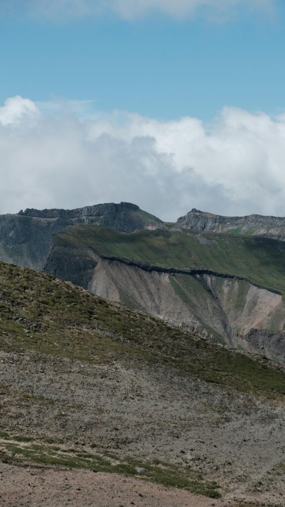 Majestic Alpine Mountain Peak with Rolling Grassy Slopes Wallpaper