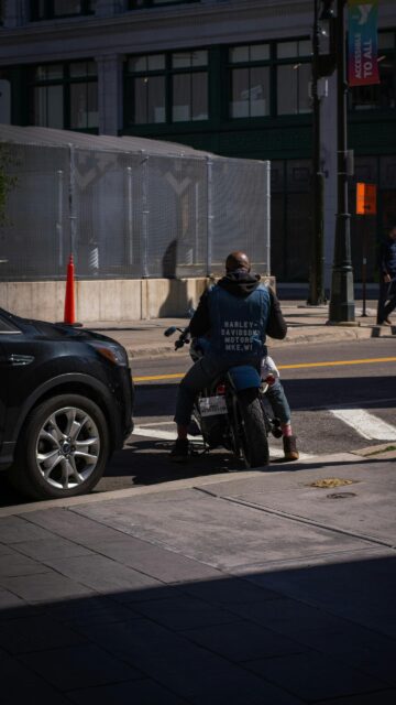 Biker Riding Harley Davidson Through City Streets Mobile Wallpaper