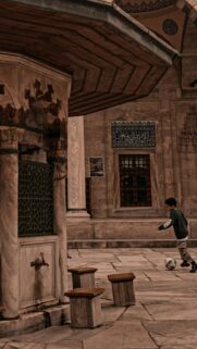 Young Boy Playing Football in a Historic Courtyard Phone Wallpaper