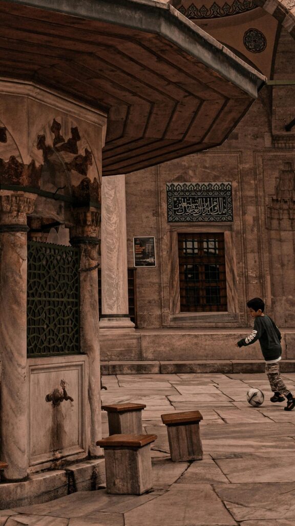 Young Boy Playing Football in a Historic Courtyard Phone Wallpaper