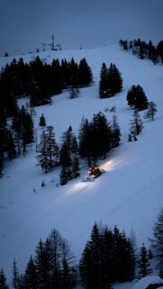 Snow Groomer on Snowy Mountain Slope at Twilight Mobile Wallpaper