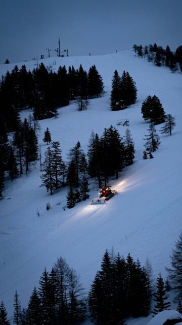 Snow Groomer on Snowy Mountain Slope at Twilight Mobile Wallpaper