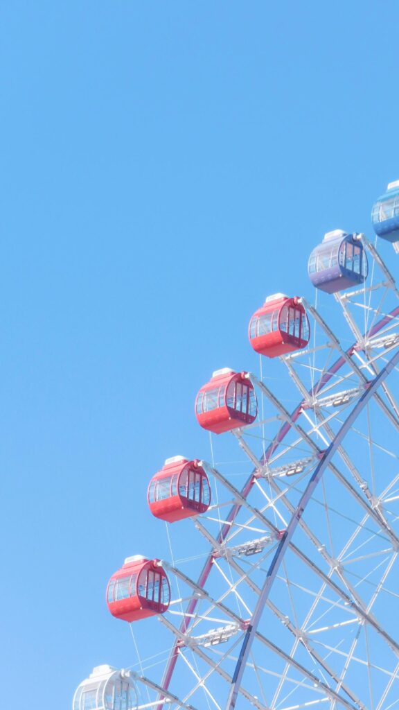 Ferris Wheel Red and Blue Gondolas Against Clear Blue Sky Wallpaper