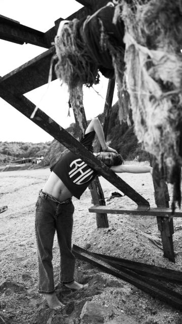 Aesthetic Male Model Posing Against Industrial Beach Structure Wallpaper