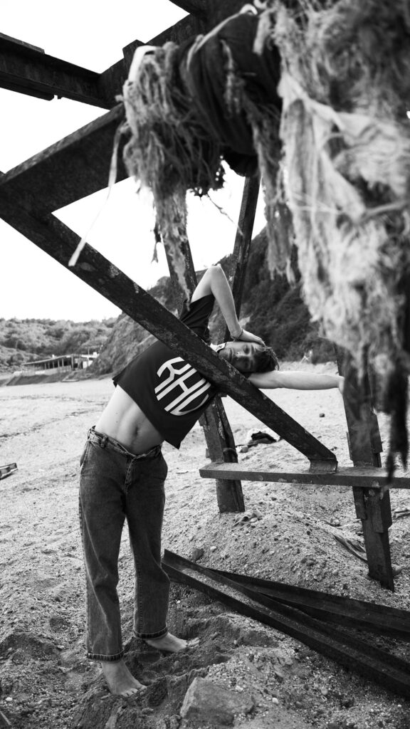 Aesthetic Male Model Posing Against Industrial Beach Structure Wallpaper