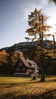 Cozy Wooden Cabin Under Mountain Cliffs Autumn Nature Wallpaper