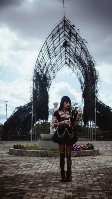 Gothic Girl With Book Under Metal Archway Mobile Wallpaper