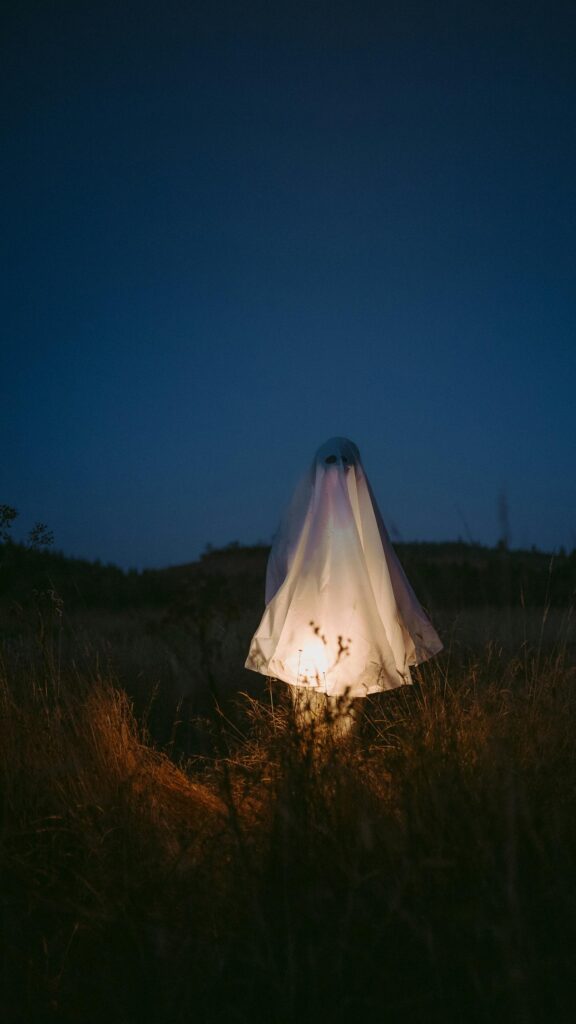 Eerie Glowing Ghost in Dark Field Mobile Phone Wallpaper