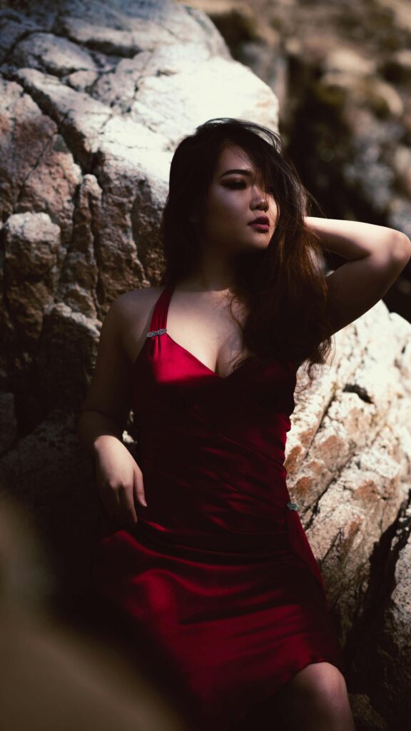 Asian Woman in Elegant Red Dress Against Rocky Background Mobile Wallpaper