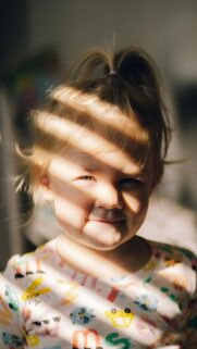 Adorable Toddler Girl with Sunbeam Shadows Portrait Phone Wallpaper
