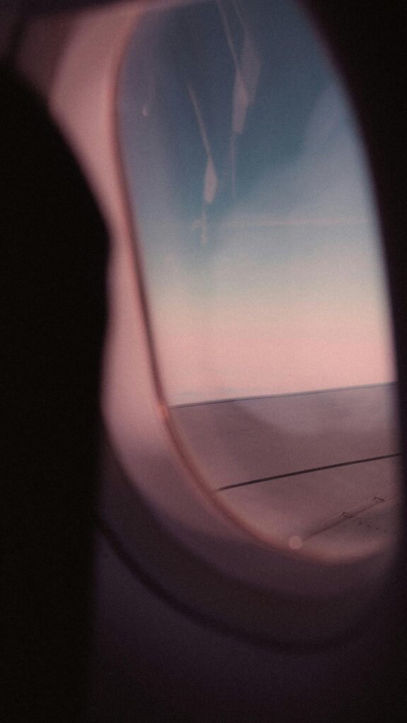 Airplane Window View with Pastel Pink Sky and Cloud Horizon Wallpaper