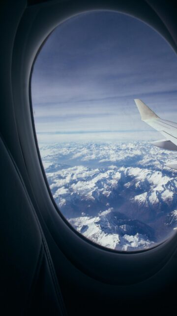 Breathtaking Aerial View of Snow Capped Mountain Peaks Airplane Window Wallpaper
