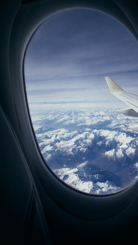 Breathtaking Aerial View of Snow Capped Mountain Peaks Airplane Window Wallpaper