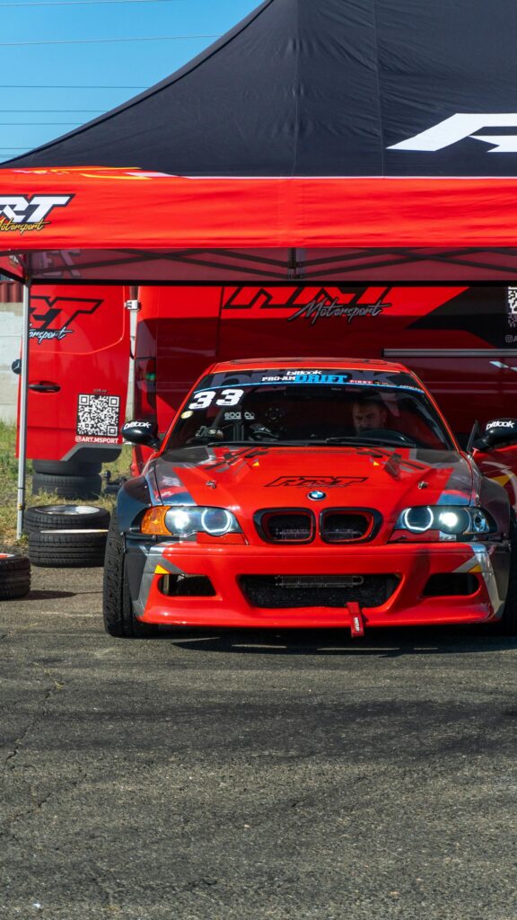 Red BMW E46 Drift Car Under Race Tent Phone Wallpaper