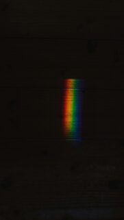 Minimalist Rainbow Light Beam on Dark Wood Texture Mobile Wallpaper
