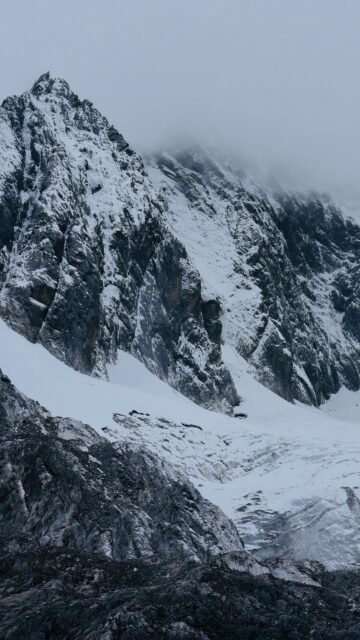 Majestic Snowy Mountain Peak Under Foggy Skies Mobile Wallpaper