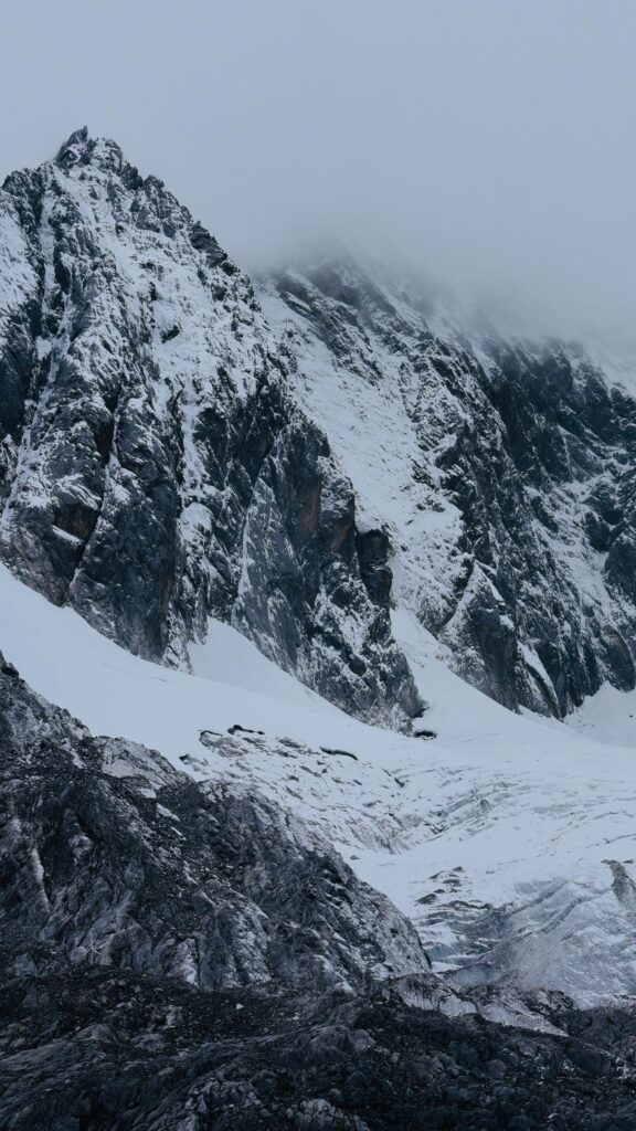 Majestic Snowy Mountain Peak Under Foggy Skies Mobile Wallpaper