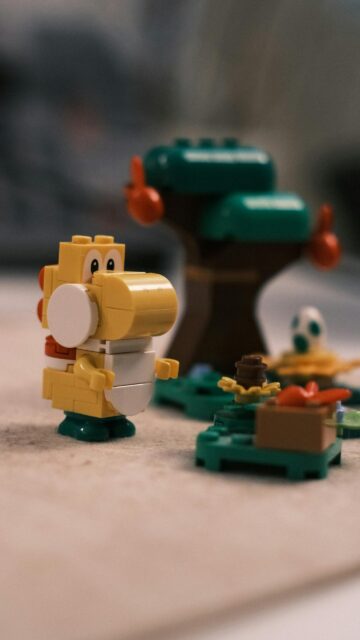 Cute Yellow LEGO Yoshi in a Mario Forest Adventure Mobile Wallpaper