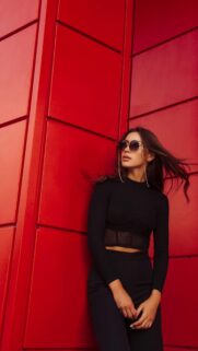 Chic Woman in Black against Vibrant Red Wall Mobile Wallpaper