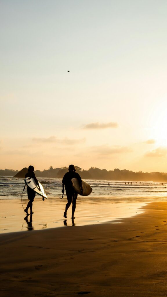 Golden Sunset Surfers Walking on Beach Mobile Phone Wallpaper
