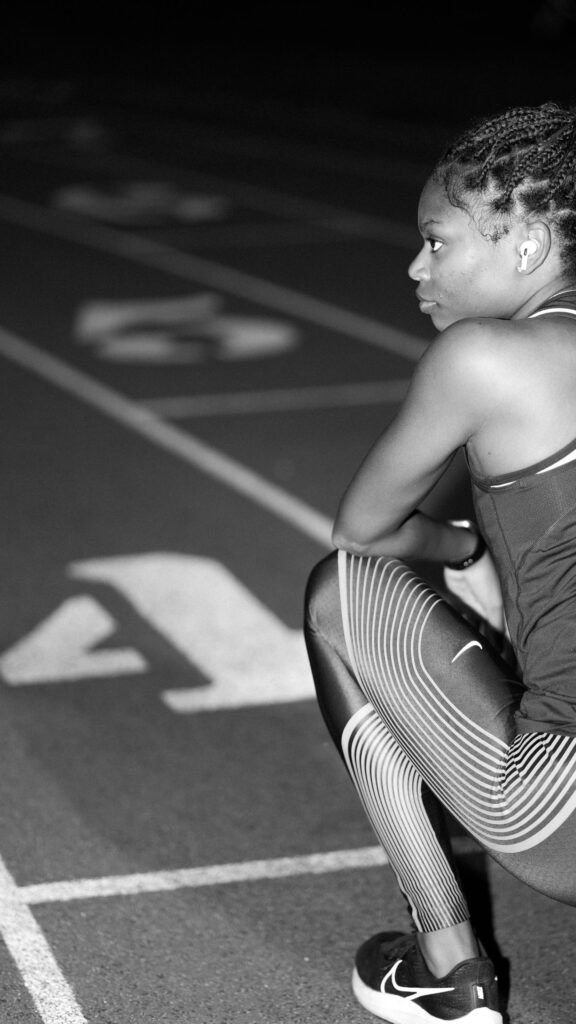 Focused Female Athlete Resting on Running Track Mobile Wallpaper